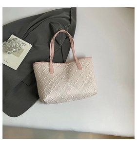 Detail showing the cream bubble textured fabric and pink leather straps of the tote bag