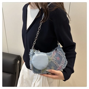 Dettaglio borsa hobo in denim vintage con stelle, bordi sfrangiati e catena metallica