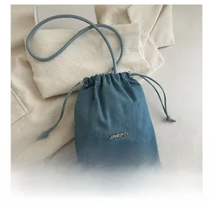 Close-up of denim bucket bag showing JINGPIN metal logo and drawstring closure details
