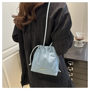 Light blue denim bucket bag with gold logo and drawstring strap shown on person