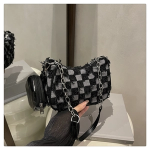 Détail du sac bandoulière en denim damier avec bords effilochés et chaîne argentée
