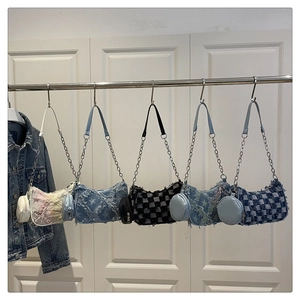 Dettaglio di borse sottobraccio in denim con frange vintage e catene argentate