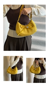 Detail view of yellow faux suede crescent tote with bow and heart charm on adjustable strap