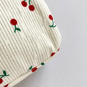 Gros plan sur le tissu en velours côtelé blanc avec broderie cerise détaillée