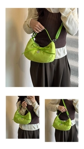 Detail of neon green crescent tote bag with suede texture, bow knot, and heart pendant