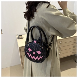 Pumpkin-shaped crossbody bag with pink spider web embroidery worn with an olive coat