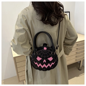Close-up of black pumpkin shaped crossbody bag with pink embroidery on model