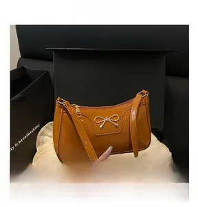 Detailed macro view of caramel patent leather bag with a gold bow hardware accent