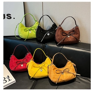Detail view of six colorful suede hobo bags with bows and heart pendants on a sofa