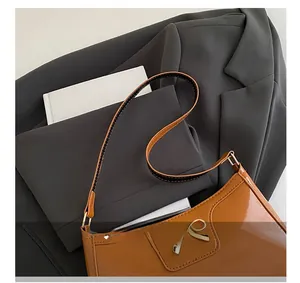 Macro detail of glossy brown leather bag with metallic bow buckle on gray blazer