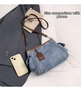 Blue canvas tote bag with adjustable strap and side pocket, shown next to a smartphone