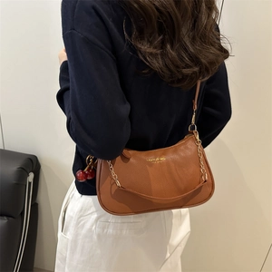 Braune Leder-Unterarmtasche mit Metallkette und Kirsch-Anhänger am Model gezeigt