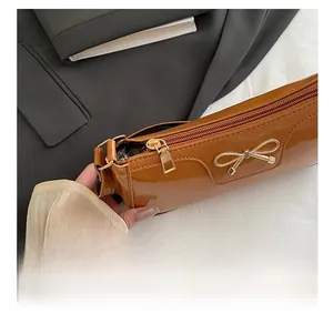 Detail shot of the smooth metal zipper and brown glossy faux leather texture of the bag