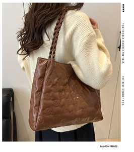 Detailed view of brown tote bag with bear embossing and woven leather handles
