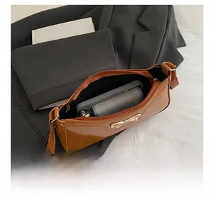 Interior view of brown glossy underarm bag showing capacity with phone and wallet