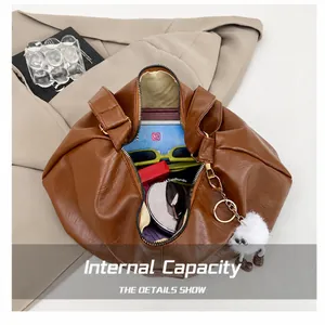 Internal capacity of brown pleated shoulder bag showing daily essentials and monster charm