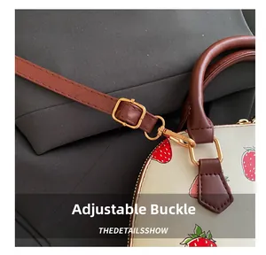 Gros plan sur la boucle dorée réglable et l'imprimé fraise du sac à main femme