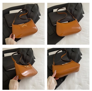 Detail view of caramel patent leather baguette bag with a gold bow metal accent