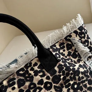Detalle del bolso tote de leopardo con flecos blancos y asa negra reforzada