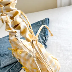 Detail der gelben Gingham-Tasche mit geruschtem Griff und sicherem Reißverschluss