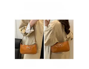 Caramel patent leather baguette bag with gold bow detail shown in hand-carry and shoulder styles