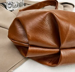 Close-up of caramel brown leather handbag showing pleated bottom detail and texture