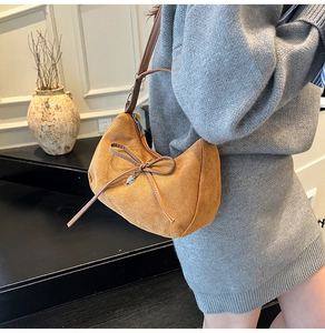 Borsa hobo in camoscio marrone con fiocco in pelle e ciondolo a cuore su una modella