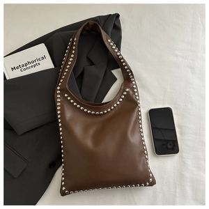 Detail einer braunen Lederschultertasche mit Silbernieten und urbanem Ästhetik-Layout