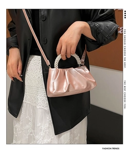Detailed macro view of pink satin cloud bag with elegant pearl-embellished round handle