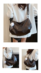 Detail of a crescent black PU leather shoulder bag with white plush ball charm