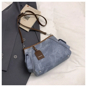 Close-up of grey blue canvas bucket bag with brown leather trim and fashion tag detail