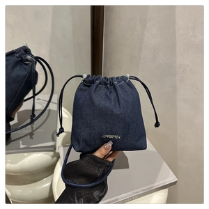 Detail der blauen Denim-Beuteltasche mit goldenem JINGPIN-Metalllogo und Kordelzugverschluss
