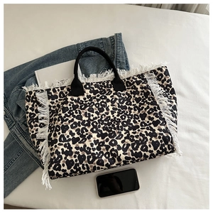 Primer plano del bolso tote de leopardo con flecos blancos y asas negras cortas