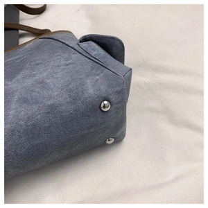 Detail einer blauen Denim-Tragetasche mit braunem Lederbesatz und silbernen Nieten