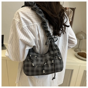 Detail der karierten Falten-Tasche mit schwarzen Schleifen und metallischen Perlen