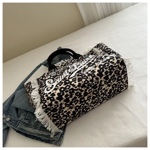 Primer plano del bolso tote de leopardo con detalles de flecos blancos y asas negras