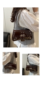 Detail of dark brown patent leather shoulder bag with punk silver rivets and buckle