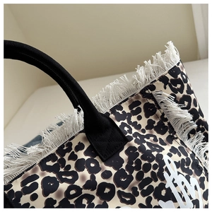 Primer plano de bolso tote de lona con estampado de leopardo y flecos blancos