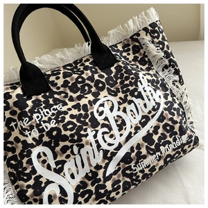 Primer plano del bolso tote de lona con estampado de leopardo, flecos blancos y asas negras