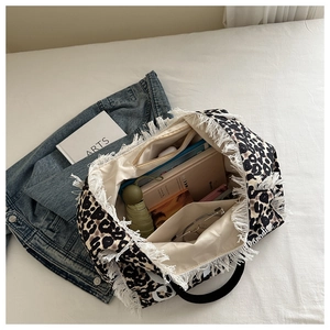 Vista de detalle del bolso tote de mezclilla leopardo mostrando forro interior y flecos