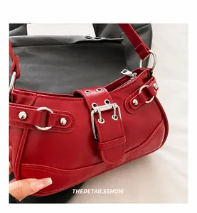 Detail of red faux leather shoulder bag with silver buckles and punk style rivets