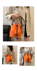 Détail du sac seau en nylon orange vif avec une bandoulière tissée à motifs