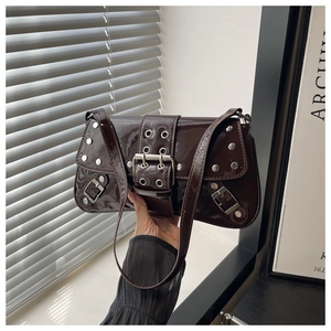 Detailed close-up of dark brown patent leather shoulder bag with silver studs and belt buckle