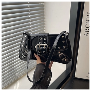 Detailed view of black patent leather shoulder bag with silver rivet studs and buckles