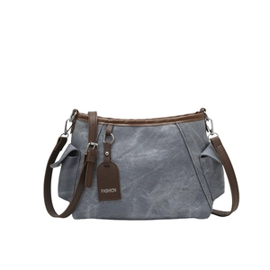 Blaugraue Canvas-Beuteltasche mit braunem Lederbesatz und modischem Anhänger
