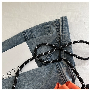 Détail du sac seau orange avec bandoulière en corde tressée contrastée noir et blanc