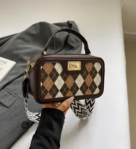 Detail of checkered crossbody bag showing gold metal buckle and wide geometric strap