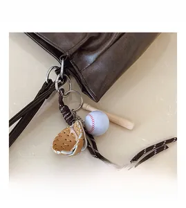Detail of vintage tote bag featuring baseball glove, ball, and bat charm accessories