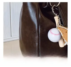 Detailed close-up of dark brown textured leather tote with baseball charm accessories