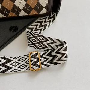 Detail of adjustable geometric strap with gold buckle on plaid shoulder bag